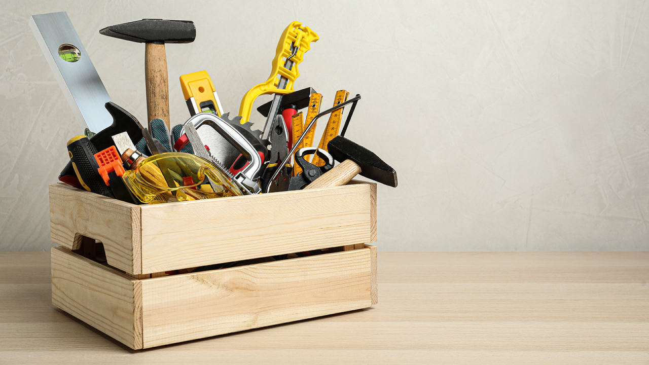 Caja llena de diferentes herramientas de carpintero sobre una mesa de madera.